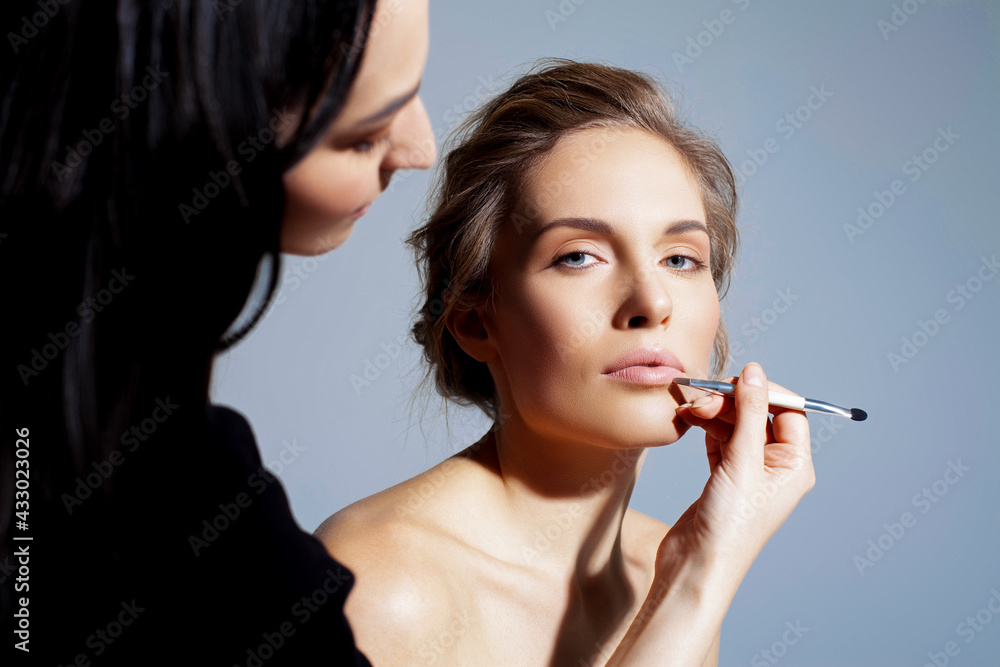 Fototapeta premium Applying natural makeup on a beautiful woman. Lipstick correction by a make-up artist