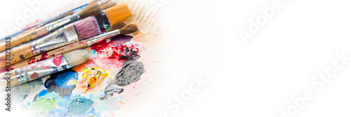 Used paintbrushes on a colorful painter palette. Paint concept panoramic background