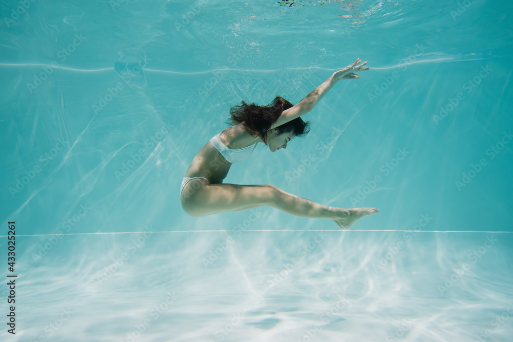 graceful young woman in swimsuit swimming in pool