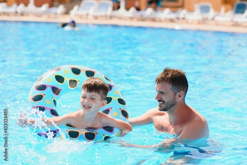 Father and son having fun in swimming pool. Family vacation