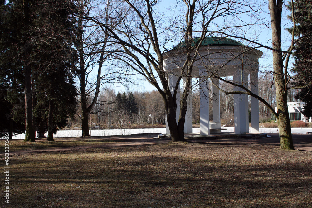 Beautiful gazebo with white columns in the park. View of the frozen lake. Beautiful gazebo with white columns in the park. View of the frozen lake.