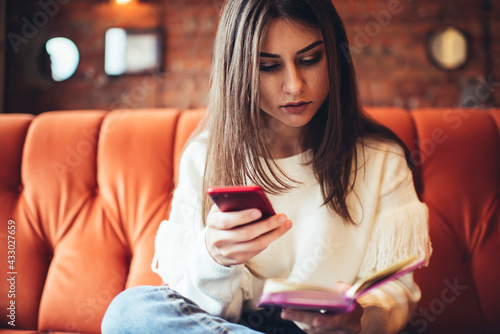 Focused woman surfing smartphone and reading notebook photo