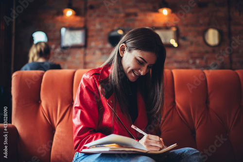 Cheerful woman taking notes in notebook