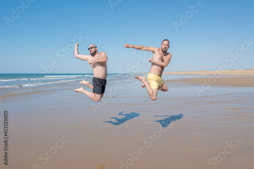 friends jumping and having fun on a lonely beach on a sunny day. friendship, union, leisure and vacation concept