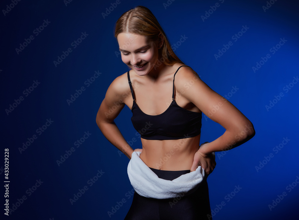 Obraz premium Image of a caucasian blonde woman in a tracksuit smiling with a towel