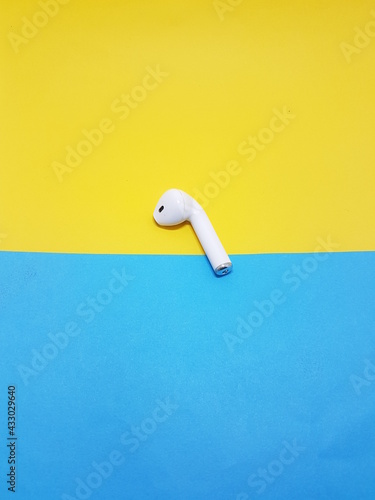 white airpod plced on yellow and sky bckground photo