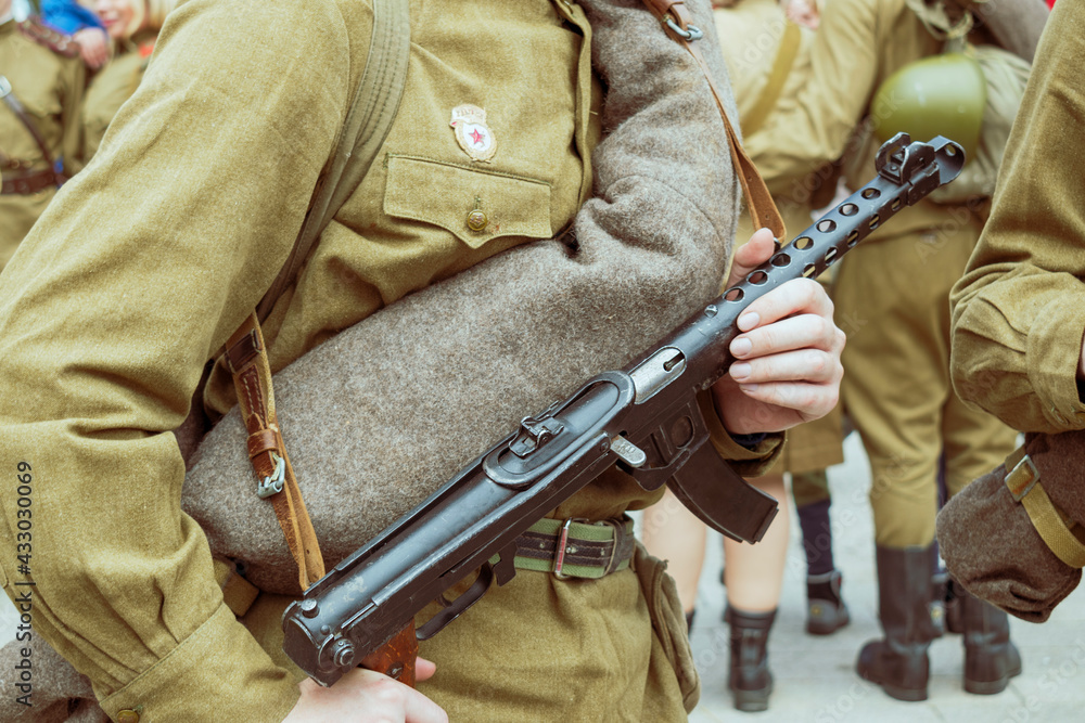 A Soviet soldier of the Second World War stands in a khaki field uniform. Weapon submachine gun close-up.