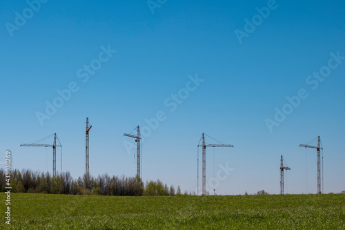 Six construction cranes against a blue sky. Copy space.. Construction of a new building.