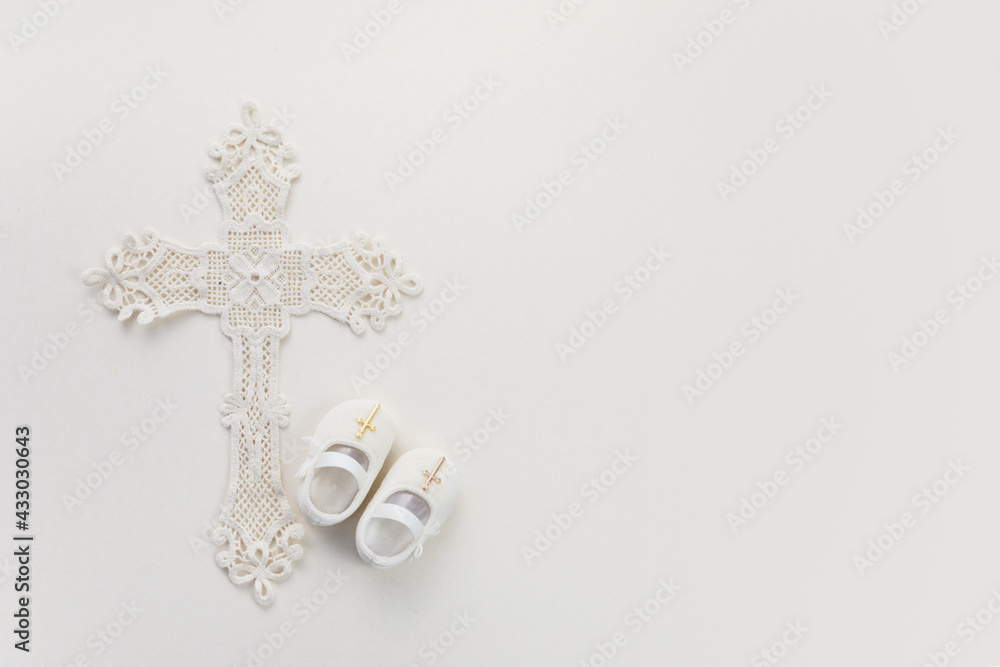 Christening background with baptism baby shoes, and cross on pastel