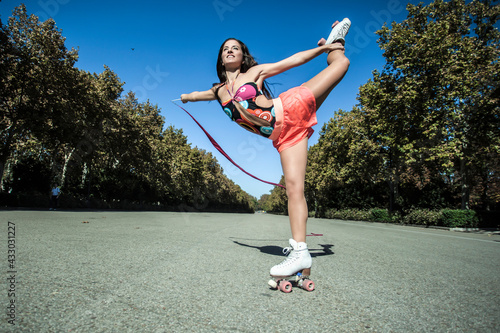 skater girl doing rhythmic gymnastics with ribbon in a park