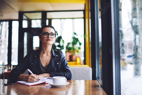 Pensive female freelancer with notebook in cafeteria