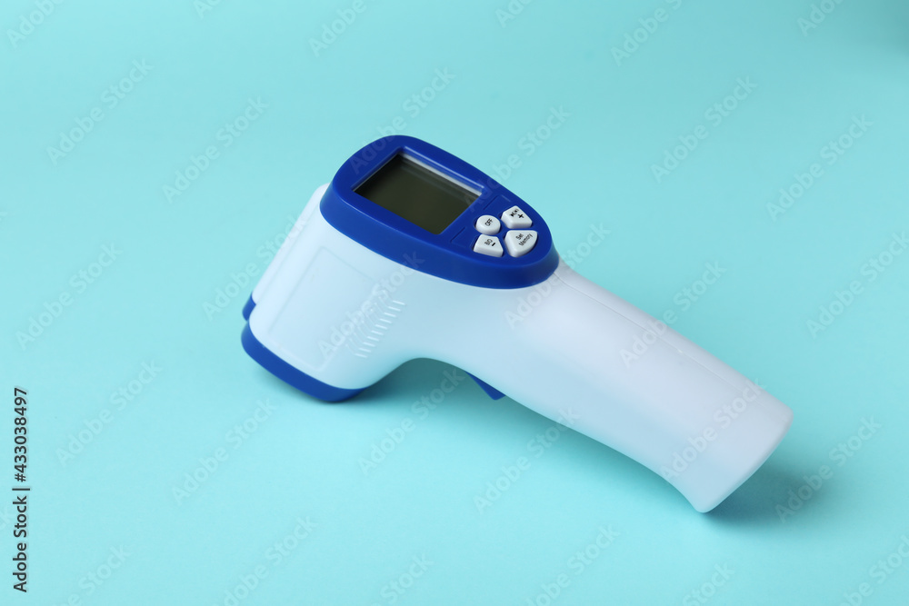 Thermometer gun on blue background, close up Thermometer gun on blue background, close up