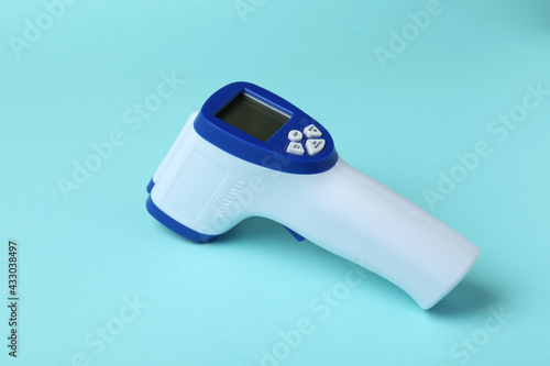 Thermometer gun on blue background, close up