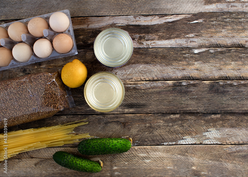 Food supplies. Buying food on a wooden background. Eggs, canned food, pasta, vegetables on a wooden background