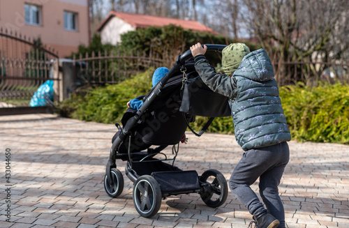 child pushing a stroller with a toddler in,  carriage