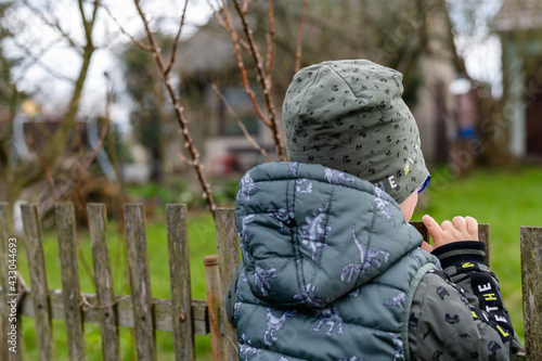 child leaning on the fence, looking in the distance