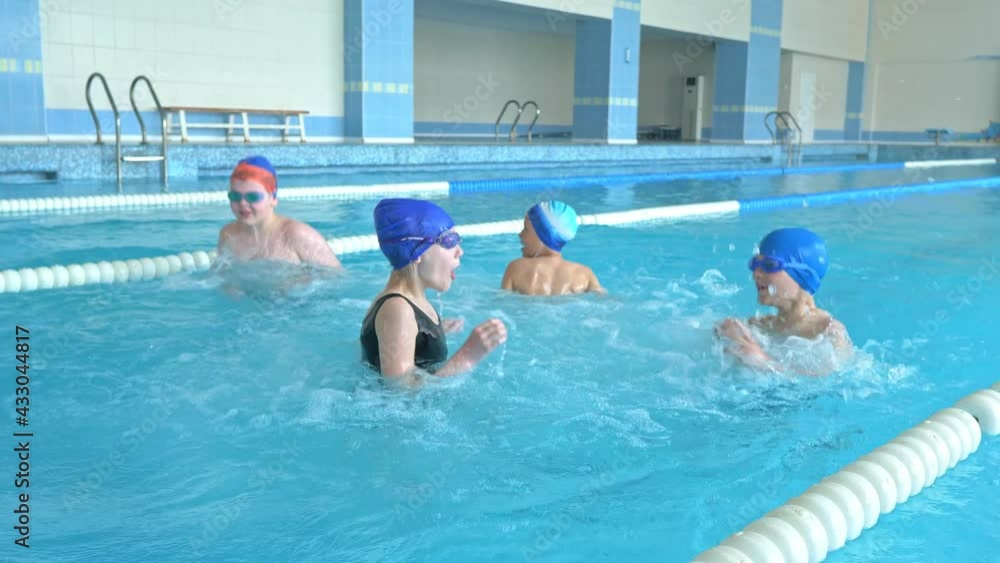 Several boys and girls jump into the pool. Children in bathing suits dive into the pool. School Swimming Section Several boys and girls jump into the pool. Children in bathing suits dive into the pool. School Swimming Section