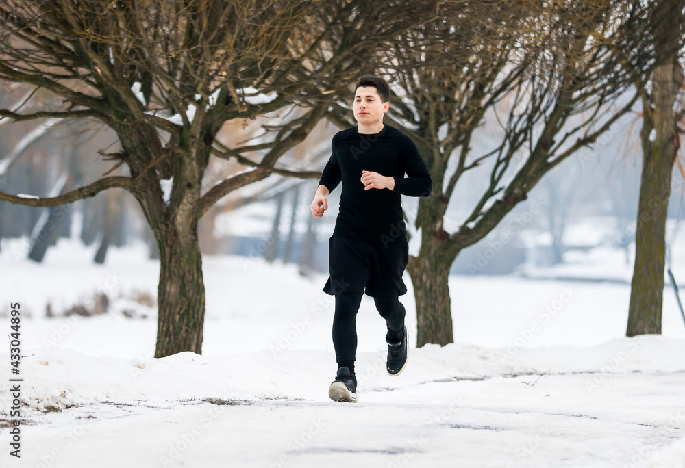 The young man goes jogging in winter while doing sports. The young man goes jogging in winter while doing sports.