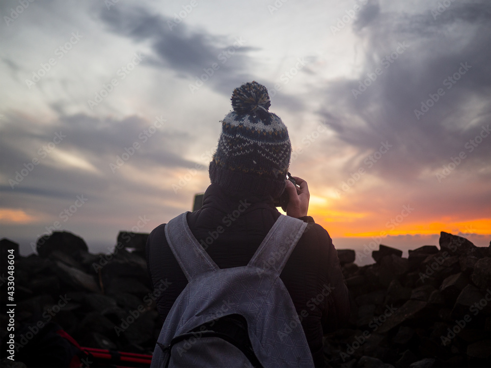 Man taking photos at sunrise on top of mountain in Ireland