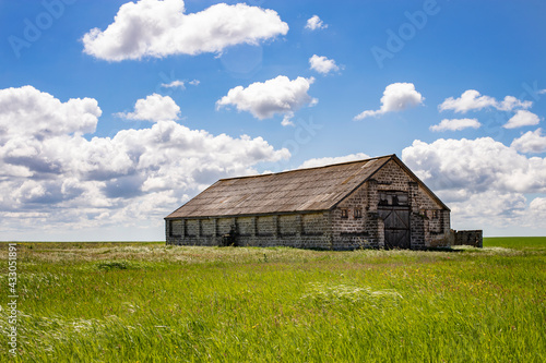 Old abandoned house made of stone on a background of sky and grass. Side view. © Алекс Ренко