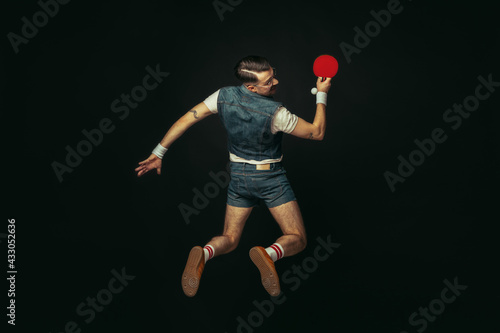 Young caucasian man playing tennis isolated on black studio background in retro style, action and motion concept © master1305