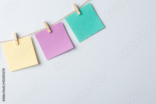 Three empty color papers on thread against white board. Copy space, message, communication concept