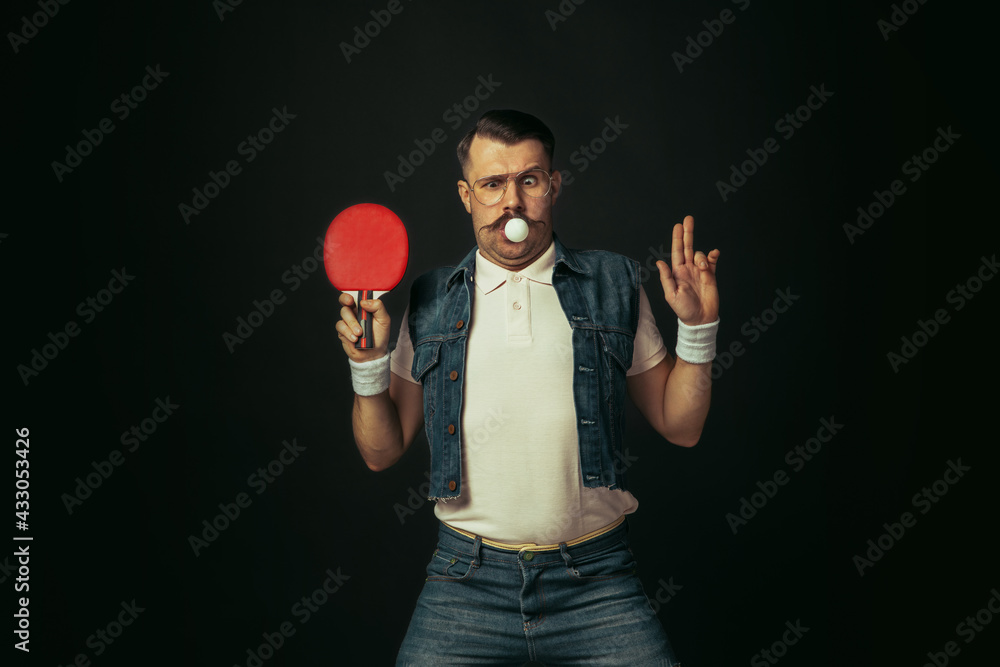 Fototapeta premium Young caucasian man playing tennis isolated on black studio background in retro style, action and motion concept