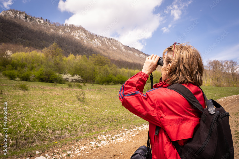 A woman looks into nature through binoculars. She is looking for animals in the forest. A woman looks into nature through binoculars. She is looking for animals in the forest.