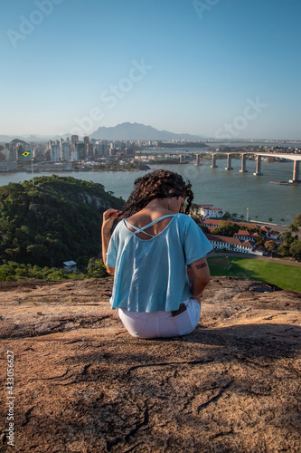 Curly girl on the top of mountain with the view of tropical beach and sea