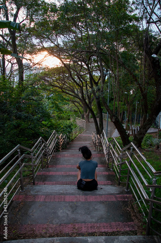 curly latin girl relax on tropical road, curly latin woman sitting in a tropical park