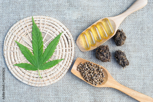 Cannabis leaves. Seeds and pills in a wooden spoon. Placed on a brown background. Cannabis and medical concept have text space.