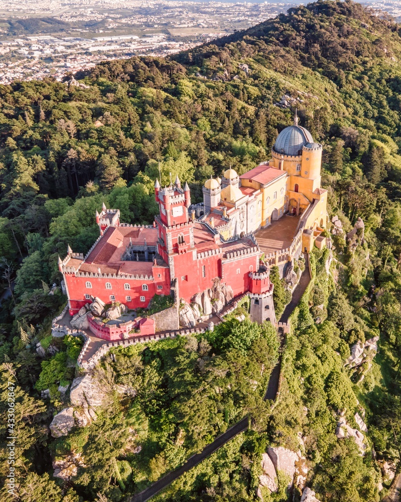Aerial view of Pena Palace, a colourful Romanticist castle building on hilltop during a beautiful sunset, Sintra, Lisbon, Portugal.