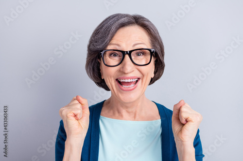 Portrait of attractive cheerful amazed lucky intellectual gray haired woman celebrating isolated over grey pastel color background