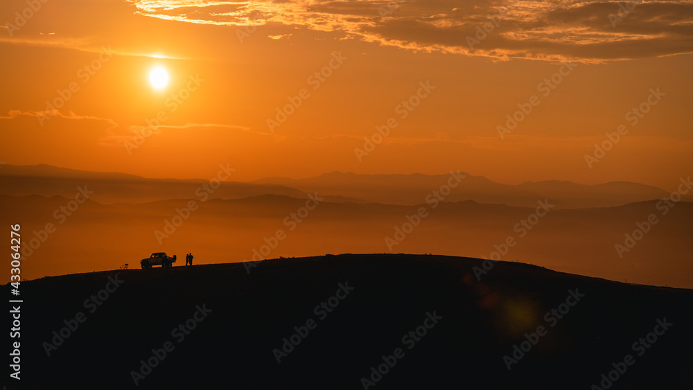 Silhouette of a couple standing on the mountain with their car, Pua District, Nan Province, Thailand Silhouette of a couple standing on the mountain with their car, Pua District, Nan Province, Thailand