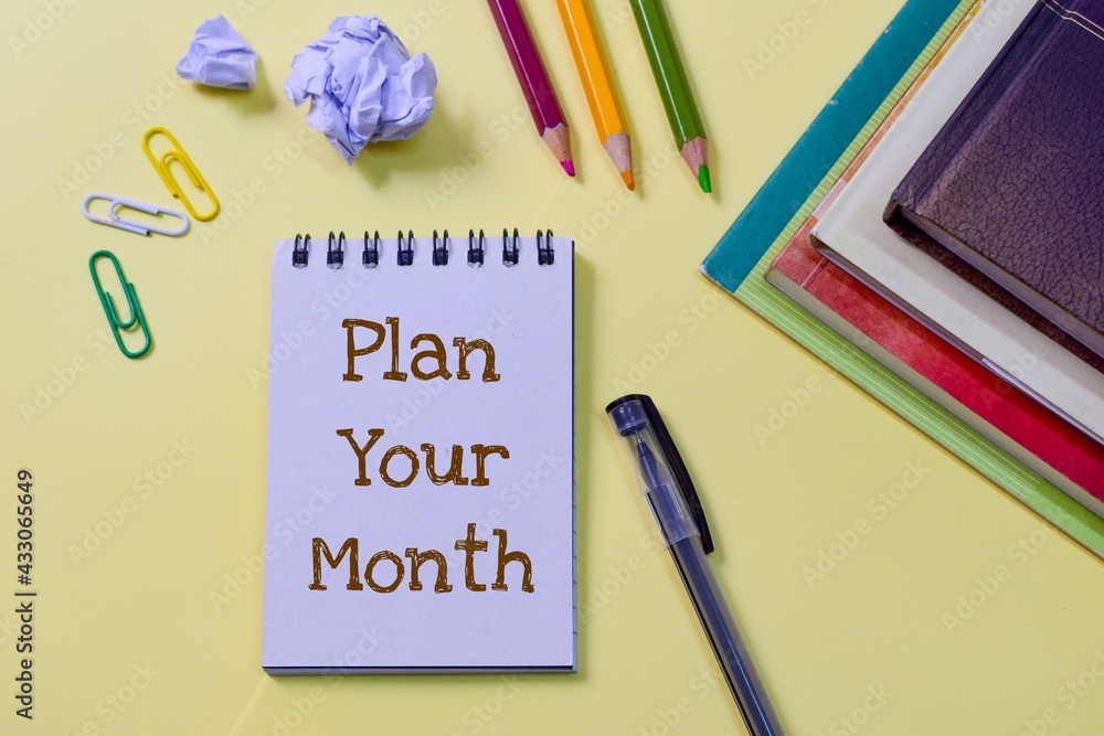 A notepad with the text Plan Your Month laid on yellow background. Concept of monthly planning process, top view. A notepad with the text Plan Your Month laid on yellow background. Concept of monthly planning process, top view.
