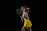 Young caucasian woman playing tennis isolated on black studio background in action and motion, sport concept