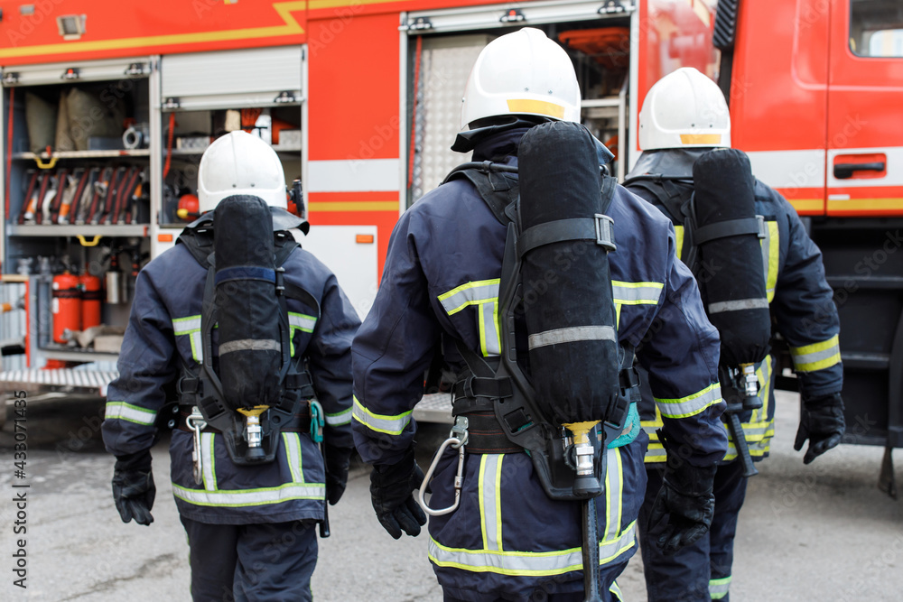 Portrait of firefighter in uniform in front of fire engine machine and fireman team Portrait of firefighter in uniform in front of fire engine machine and fireman team