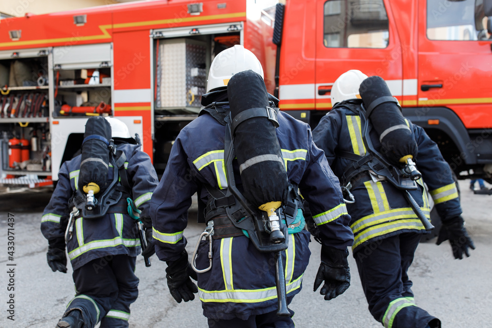 Portrait of firefighter in uniform in front of fire engine machine and fireman team Portrait of firefighter in uniform in front of fire engine machine and fireman team