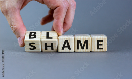 Blame or shame symbol. Businessman turns wooden cubes and changes the word 'shame' to 'blame' or vice versa. Beautiful grey background, copy space. Business, blame or shame concept.