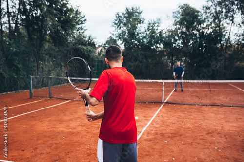 man playing tennis outdoors on clay court