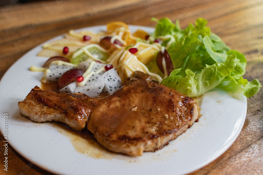 Pork steak and vegetable salad in white plate Pork steak and vegetable salad in white plate