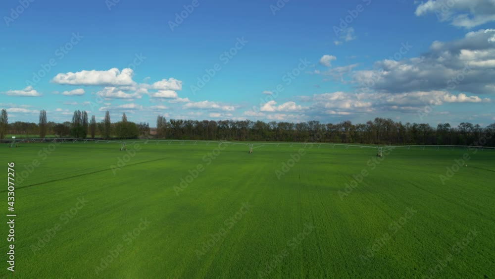Irrigation system on agricultural land aerial view. Green grass field and sky. Irrigation system on agricultural land aerial view. Green grass field and sky.