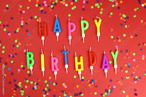 Colorful happy birthday candles on a red background