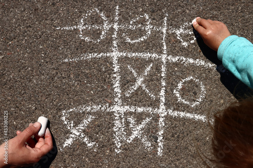Canvastavla child plays with his mother in tic-tac-toe chalk on the asphalt