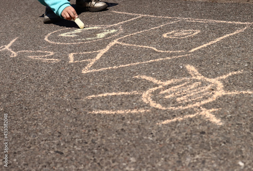 child draws pictures with chalk on the asphalt