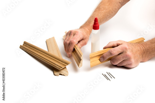 craftsman's hands getting ready to glue molding to make a picture frame isolated on white
