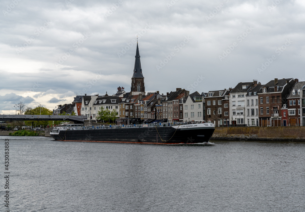 river barge travels upriver on the Maas River in downtown Maastricht