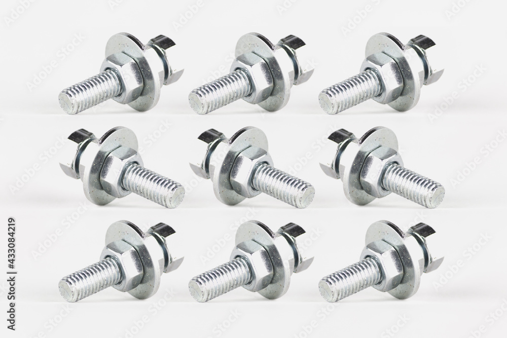 Texture and repetitive pattern of screws, nuts and washers, created by photo composition, on a white background. All the pieces are identical, but look in different directions. Texture and repetitive pattern of screws, nuts and washers, created by photo composition, on a white background. All the pieces are identical, but look in different directions.