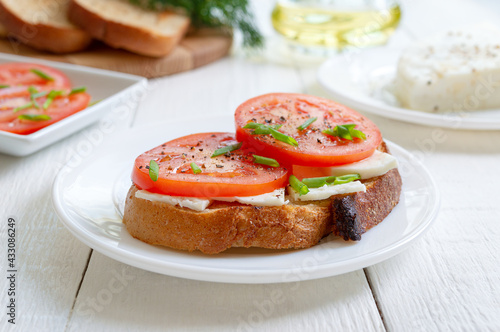 Whole grain bread with goat cheese and fresh tomatoes on white. Healthy and tasty breakfast.