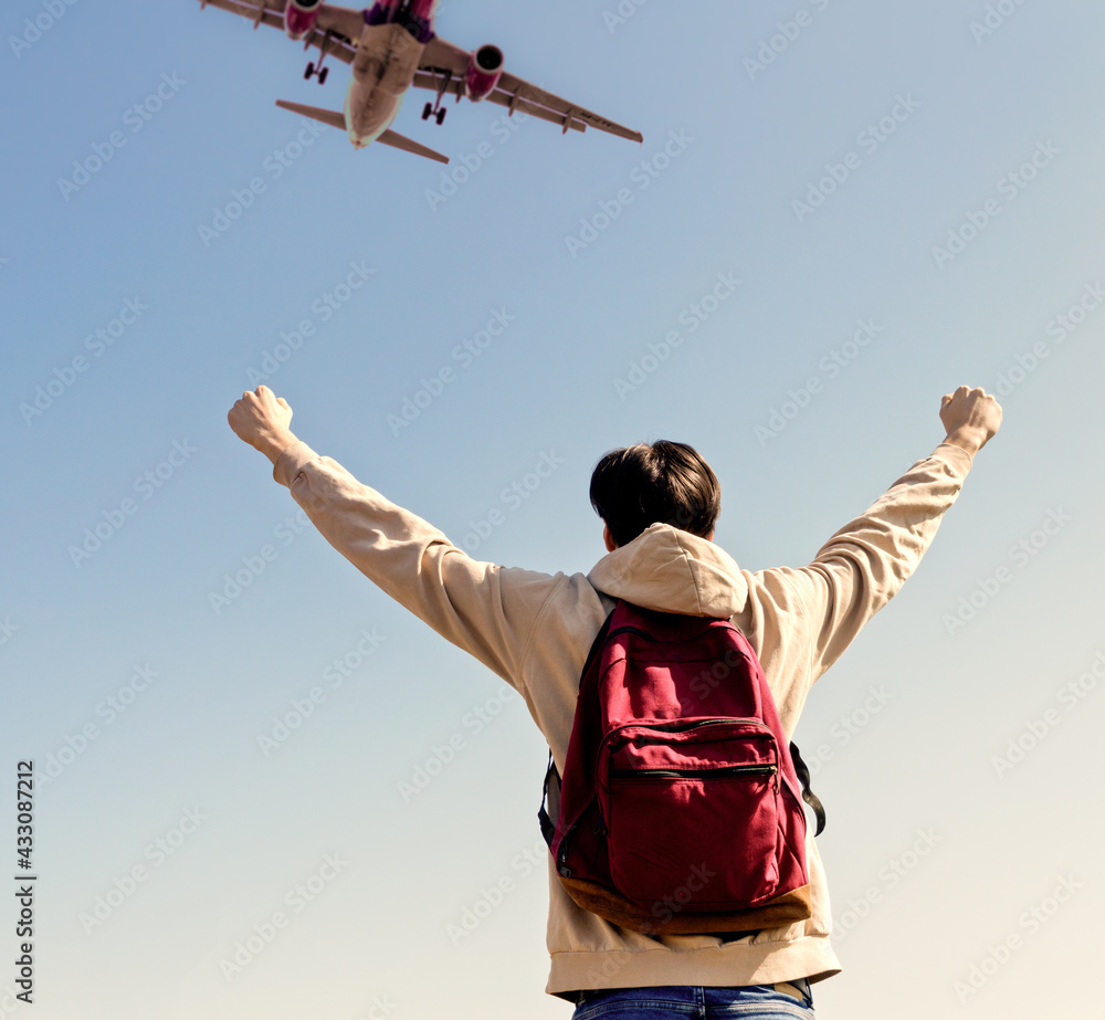 Back view of Young man with his hand raised on the airport runway Back view of Young man with his hand raised on the airport runway